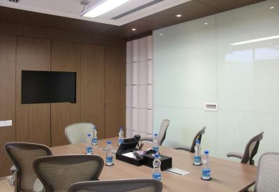 Modern meeting room with a wooden table, ergonomic chairs, and wall-mounted screen.