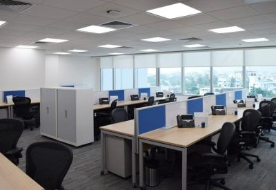Large open-plan office space with rows of desks and blue partitions.