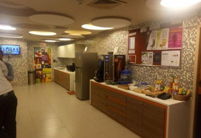 Communal kitchen and break area with coffee machines, snack counter, and patterned wallpaper.