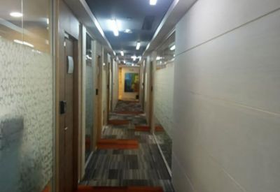 Long office corridor with glass walls and striped carpet tiles.