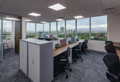 Open-plan workspace with multiple ergonomic desks and expansive city views through large windows.