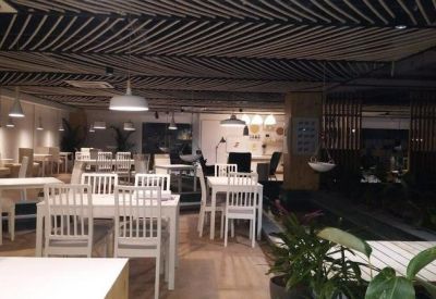 Dining area with white wooden tables, chairs, and a unique striped ceiling design.