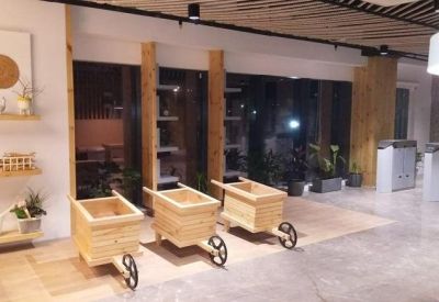 Reception or entry hall with wood cart displays, potted plants, and sleek flooring.