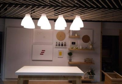 Minimalist display area with white tables and bright pendant lights against a clean wall.