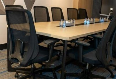 Professional meeting room with a large wooden table and black mesh chairs.