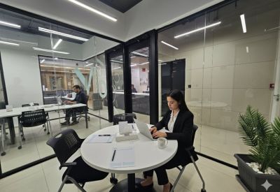Bright glass-partitioned workspace with a circular meeting table and a potted plant.