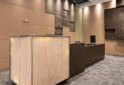 Sleek reception desk with light wood paneling and stone feature wall.