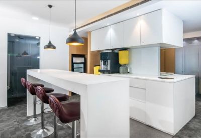 Sleek modern pantry and break area with white cabinetry and a high breakfast bar.