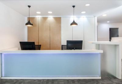 Bright reception desk with a backlit blue glass panel and modern pendant lighting.