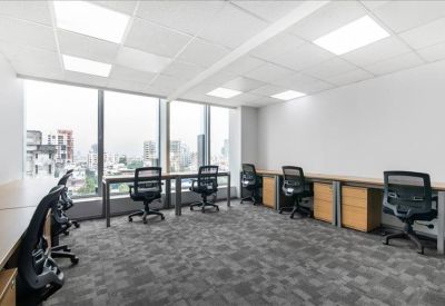Spacious open-plan workspace with rows of desks and large windows overlooking the city.