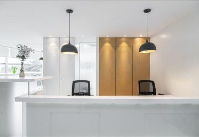 Professional reception area with a white desk, black pendant lights, and warm wooden paneling.
