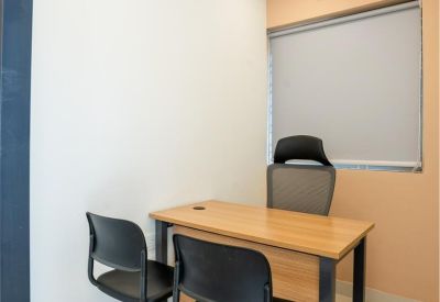 Private glass-walled office with a wooden desk and two guest chairs.