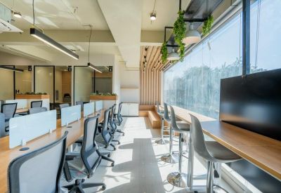 Bright workspace featuring high-top window seating and long communal desks.