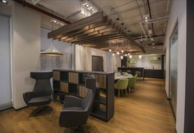 Spacious communal lounge with industrial wood ceilings and modern grey armchairs.