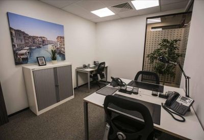 Dual-workstation office with ergonomic black chairs and frosted glass walls.