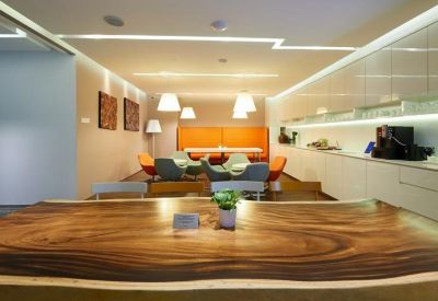 Communal break area featuring a live-edge wooden table and vibrant orange seating.