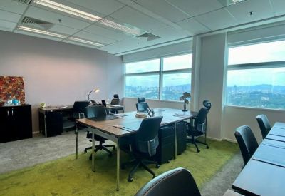 Open plan shared workspace with a bright green carpet and city views.