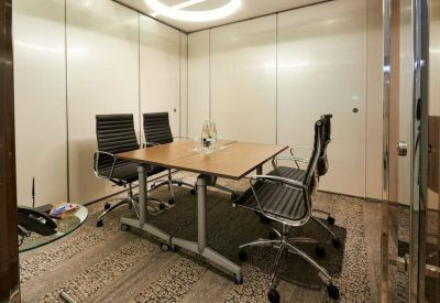 Small private meeting room with four black chairs and a light wood table.