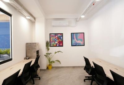 Private office with two desks, potted plant, and abstract wall art.