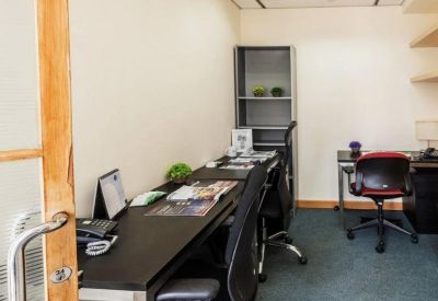 Private office suite featuring long black desks, ergonomic chairs, and a grey shelving unit.