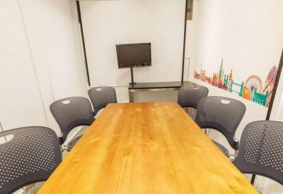 Meeting room with a central wooden table, black mesh chairs, and a wall mural of city landmarks.
