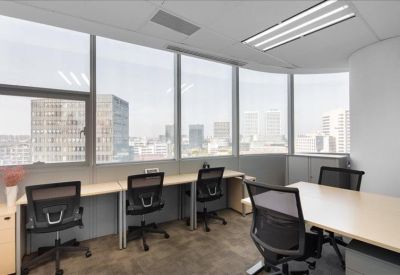 Coworking space with workstations along a curved window wall overlooking the city skyline.