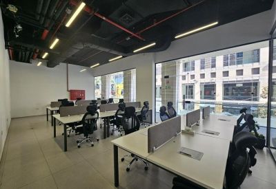 Open-plan workspace featuring rows of white desks with privacy screens and ergonomic chairs.