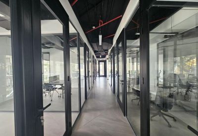 Modern office corridor lined with glass-walled private suites.