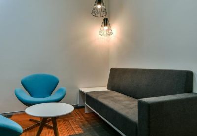 Private breakout room with a grey sofa and blue accent chairs.