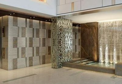 Spacious lobby with a decorative metal screen, water feature, and a large indoor plant.