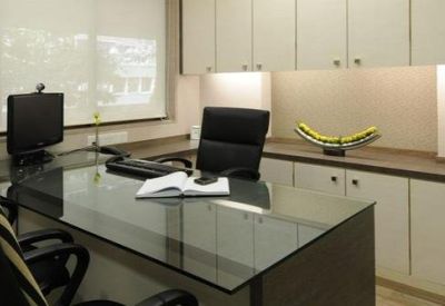 Private office suite featuring a glass-top desk, white cabinetry, and soft under-cabinet lighting.