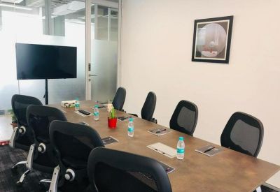 Modern conference room featuring a wooden table, ergonomic black chairs, and a flat-screen TV.