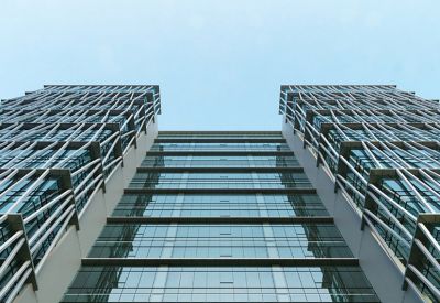 Looking up at a glass skyscraper featuring a unique white lattice geometric facade.