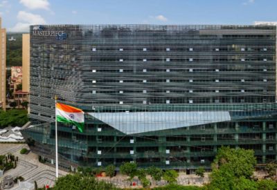 Wide view of the multi-story glass office building facade behind a waving national flag.