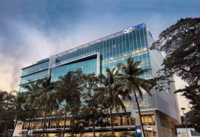 Ground-level view of a glass office building framed by tropical palm trees.