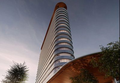 Exterior view of the curved glass facade of Redbrick Offices, Godrej GCR, rising above landscaped trees.