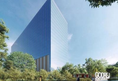 Ground level view of the modern skyscraper entrance surrounded by lush greenery.