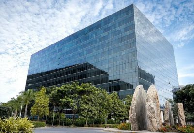 High-angle exterior view of a glass office building reflecting the sky with large decorative stones in the foreground.