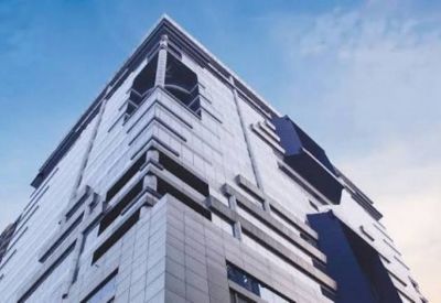 Upward view of a multi-story building facade featuring white cladding and geometric blue window frames.