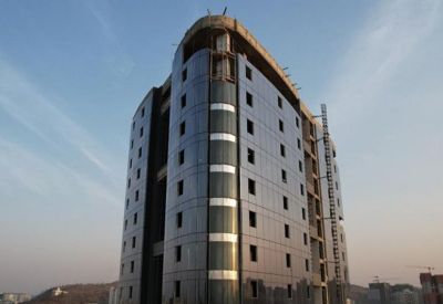 Tall commercial building with a dark glass curtain wall under a clear blue sky.