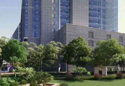 Lush green landscaping and trees in front of a grey stone and glass building exterior.