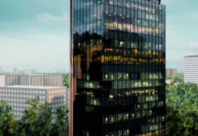 Tall glass facade building reflecting the sky and surrounding greenery.