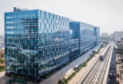 Daytime exterior view of the modern glass office complex next to a commuter rail line.