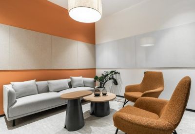 Private lounge suite with an orange accent wall, grey sofa, and two burnt-orange armchairs.