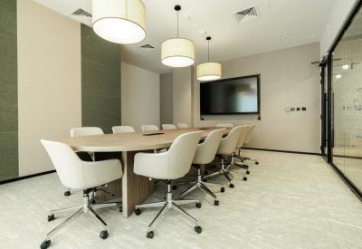 Professional boardroom with a long wooden table, white swivel chairs, and three large drum pendant lights.
