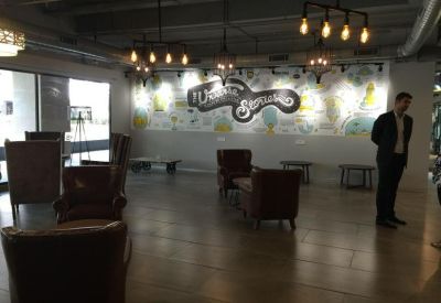 Lounge area with leather armchairs and a mural wall under industrial lighting.