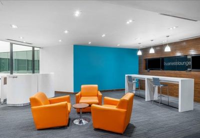 Modern breakout area with bright orange armchairs and a blue feature wall.
