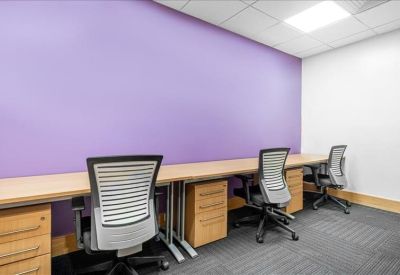 Brightly lit three-person office suite with a purple feature wall and wooden desks.