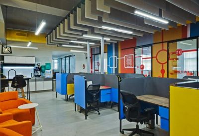 Open-plan workspace featuring blue and yellow cubicles and orange lounge chairs.