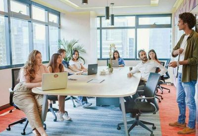 Bright meeting room with a large wooden table and city views through windows.